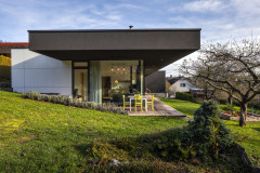 Presklené steny otvárajú centrálny obytný priestor na terasu orientovanú západným a južným smerom. Mierne zapustenie stavby do svahu umožnilo priame napojenie terasy na tejto strane na terén záhrady