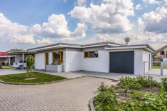 Dom stojí priamo na uličnej čiare, kryté parkovacie státie je pred ňu predsunuté