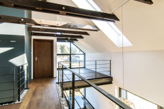 Vnútorné usporiadanie je úplne moderné. Drevený trámový strop a galéria nad spoločnou obývacou časťou akoby sa voľne vznášali v priestore. Strešnými oknami i oknom v štíte preniká veľa svetla