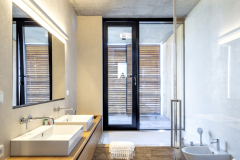 Do kúpeľní architekti navrhli hladké stierkové povrchy, ani tu nechýba prírodné drevo, na dlážke vyniká travertín