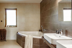 Priestranná kúpeľňa s rohovou vaňou v decentnej kombinácii béžových a hnedých veľkoformátových obkladov
