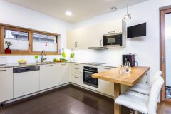 Rohová kuchyňa s príručným barovým stolíkom a dvomi barovými kresielkami s epedami