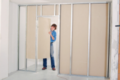 6. Opláštite prvú stranu priečky sadrokartónovými doskami Rigips. Prvú stranu priečky začnite obkladať doskami s plnou šírkou (1 200 mm), nastojato. Dosky sa pripevňujú iba na zvislé profily samoreznými skrutkami typu TN vo vzdialenostiach 250 mm. Používajte pokiaľ možno celé dosky, menšie diely iba s minimálnou výškou 400 mm. Zabezpečte, aby sa vodorovné škáry susedných dosiek vzájomne striedali aspoň o 400 mm a nedochádzalo k vytváraniu krížových škár. Pri dlážke ponechajte 10 mm širokú škáru.