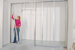 5 CW profily (stĺpiky) voľne nasuňte do vodiacich UW profilov. Rozstup stĺpikov sa volí podľa šírky dosiek opláštenia, CW profil musí byť o cca 10–15 mm kratší ako vzdialenosť medzi spodným a horným UW profilom. S pripevnením dosiek začnite na stabilnejšej strane profilov.