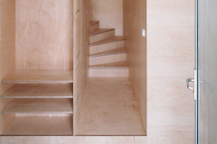 Pohľad na schodisko a šatňu z preglejky. Hoci ide o lacný materiál, pôsobí veľmi pekne. Architekti radi pracujú s kresbou dreva, ktorá na seba môže pekne nadväzovať