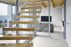 Krivočiare oceľové schodisko medzi prízemím a podkrovím je vyhotovené z oceľového plechu a tvrdého dreva. Má iba stupne bez podstupňov, konštrukcia sa kotví oceľovými kotvami do základovej dosky a do drevenej stropnice. Stupne sú z tvrdého dreva (jaseň), zábradlie tvorí lanková sieť