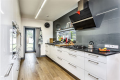 Kuchynská linka je vyrobená z bielych lakovaných MDF dosiek (Sokol Interiéry), stena pri okne je obložená sklom